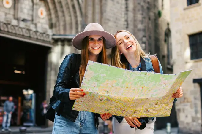 Spain, Barcelona, two happy young women reading map