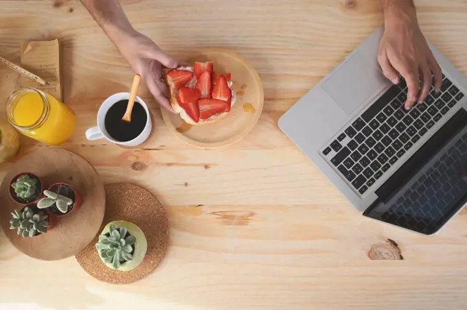 Young man using laptop while having breakfast