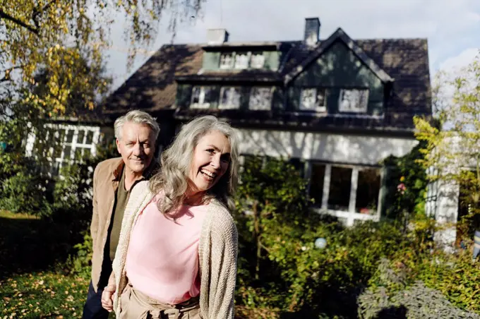 Happy senior couple in garden of their home in autumn