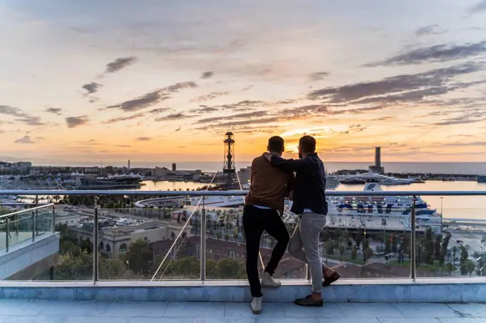 Gay couple on lookout above the city with view to the port, Barcelona, Spain