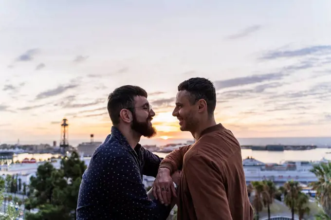 Gay couple on lookout above the city with view to the port, Barcelona, Spain