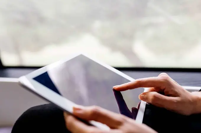 Woman's hand using a tablet while traveling by train