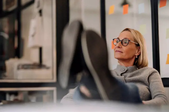 Mature businesswoman in office with feet on desk