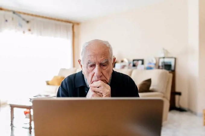 Portrait of senior man using laptop at home