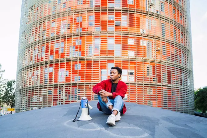 Portrait of mature man with megaphone sitting outdoors, Barcelona, Spain