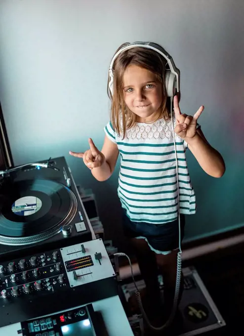 Portrait of little DJane with headphones showing Rock And Roll Sign