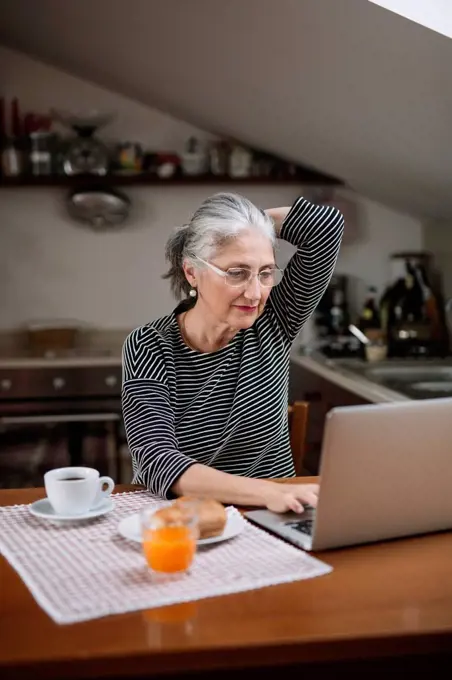 Portrait of senior woman using laptop at breakfast table