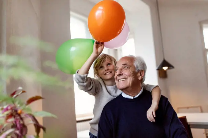 Happy grandfather and grandson playing with balloons at home