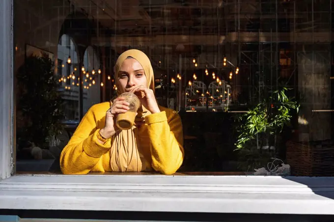 Portrait of young woman drinking smoothie in a cafe