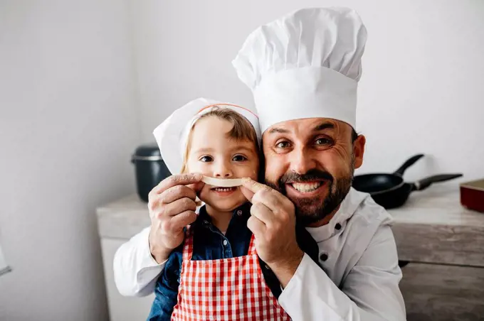 Playful father with daughter having fun while preparing homemade pasta in kitchen at home