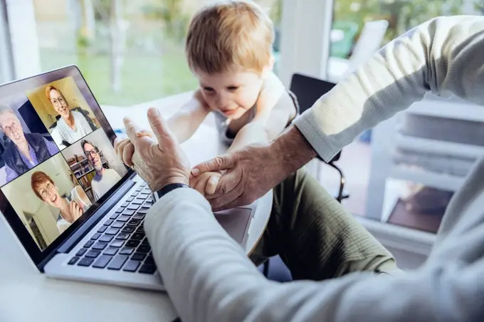 Little boy interrupting father's video conference at home