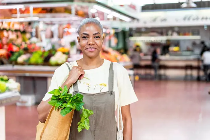 Portrait of smiling woman buying groceries in a market hall