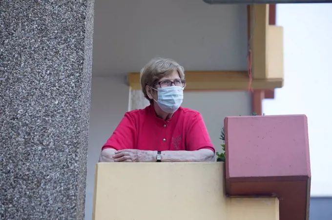 Senior woman wearing mask on balcony, retirement home