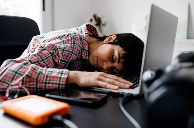 Overworked woman sleeping on laptop in home office