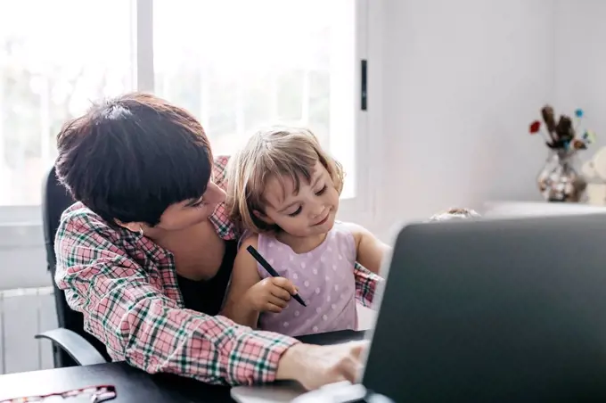 Mother working at home with her daughter