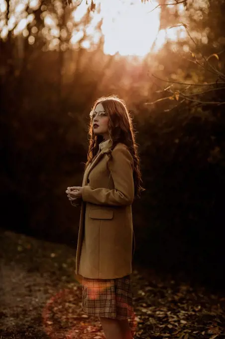 Portrait of fashionable woman in autumn standing at backlight