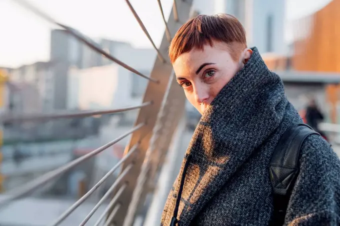 Portrait of redheaded young woman on a bridge in the city at sunset