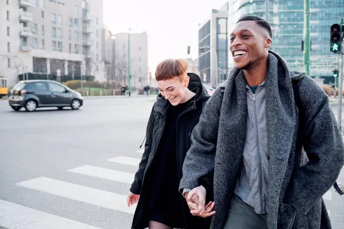 Happy young couple crossing a street in the city, Milan, Italy