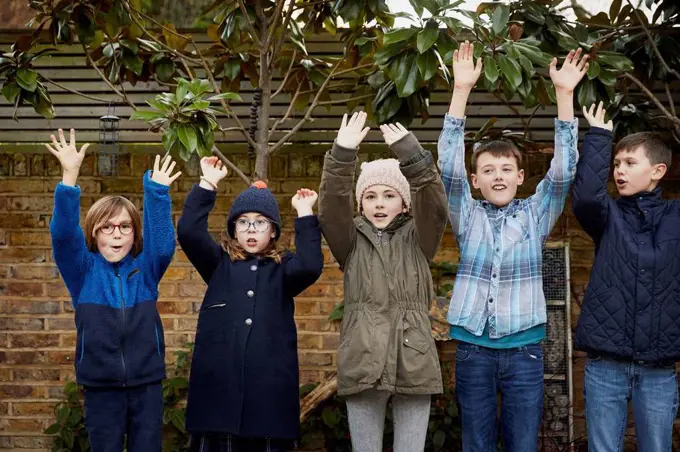 Group of children on the schoolyard raising their arms during break time