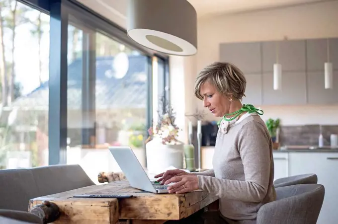 Woman working at home while using laptop at table in living room