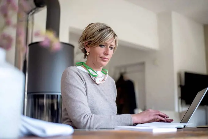 Mature woman working at home while using laptop in living room