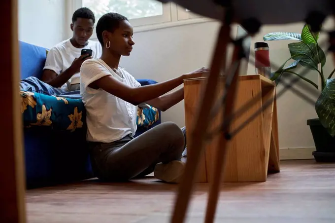 Young couple using smartphone and laptop at home