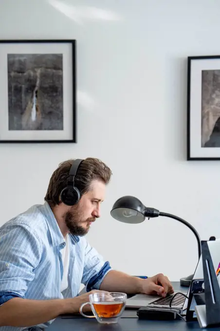 Man using laptop and headphones at home