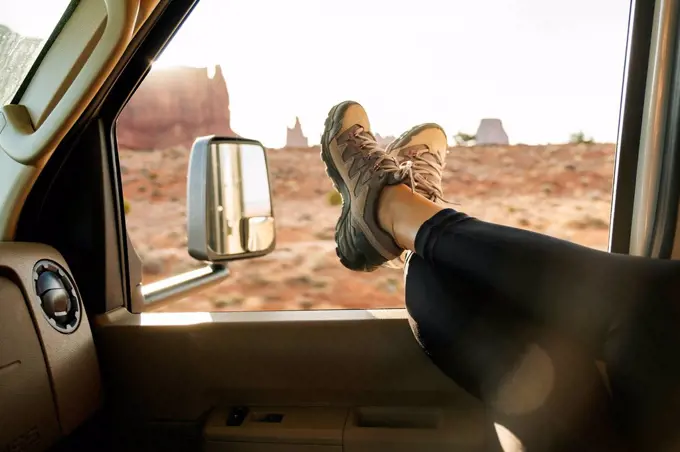 Low section of woman relaxing with feet up on vehicle window, Monument Valley Tribal Park, Utah, USA