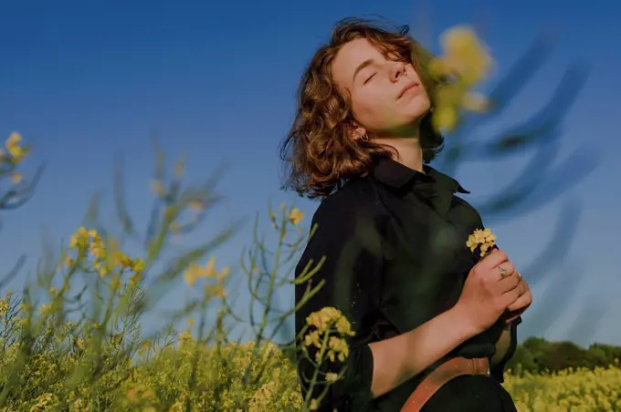 Portrait of teenage girl with eyes closed standing in rape field