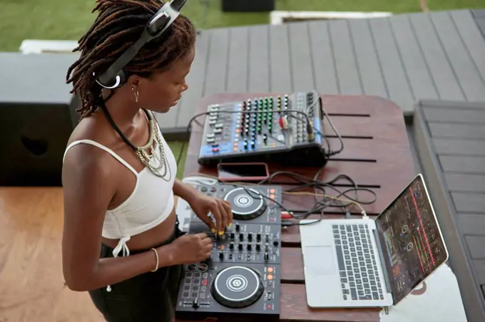 DJane working on mixing board looking at laptop