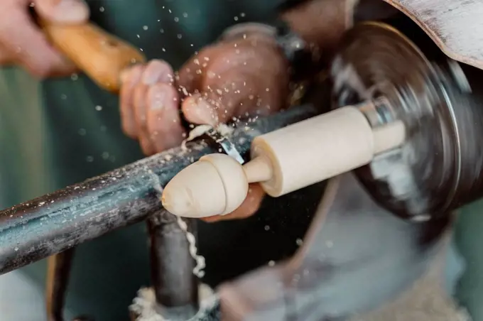 Close-up of carpenter holding chisel while shaping wood at workshop