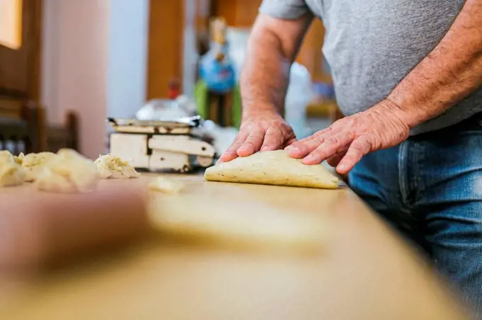 Midsection of chef preparing fresh Mona de Pascua on kitchen counter at restaurant