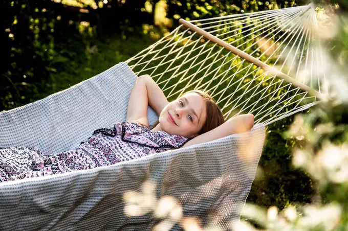 Germany, Bavaria, Landshut, Girl relaxing in hammock in garden