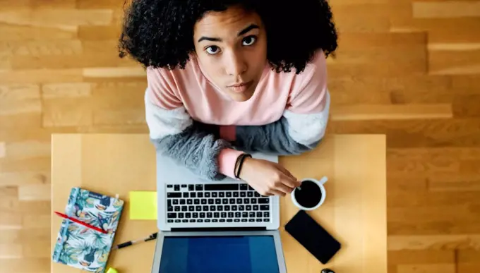 Top view of young woman sitting at desk at home