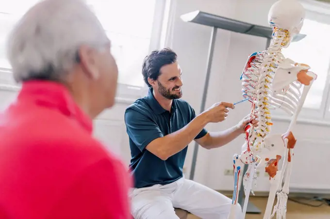 Physiotherapist explaining treatment to patient, using skeleton