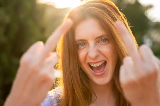 Portrait of laughing redheaded woman giving the finger