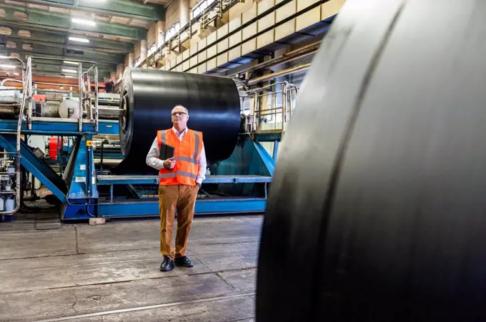 Senior man wearing safety vest in a rubber processing factory