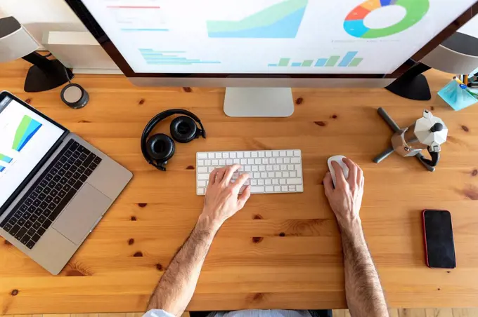 Hands of man, working from home, view from above of desk with mobile devices an coffee maker