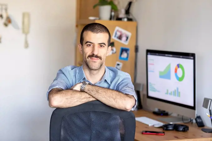 Portrait of man with home office in background