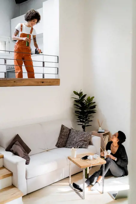 Two young women relaxing at home with Asian food and beer