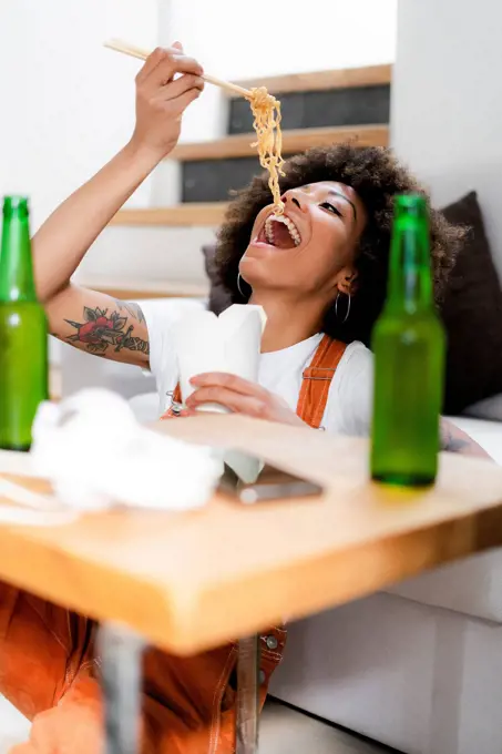 Portrait of young woman eating Asian food at home