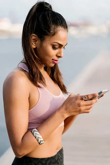 Close-up of female athlete using smart phone while standing at harbor