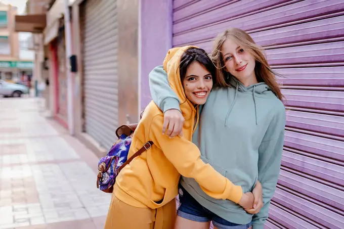 Portrait of two smiling and hugging female friends in the city