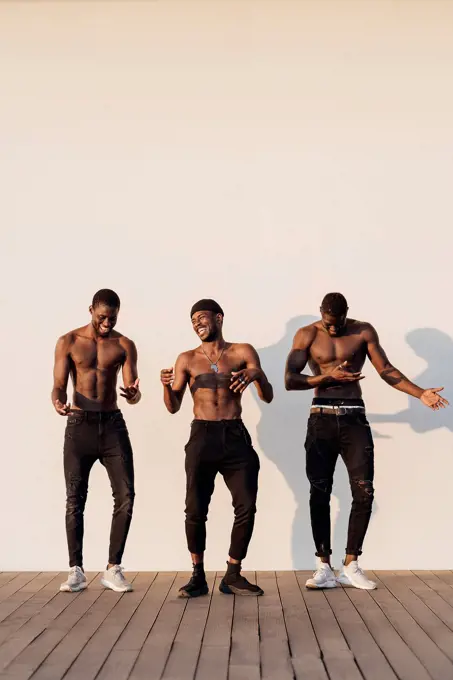 Cheerful young shirtless men standing side by side against white background