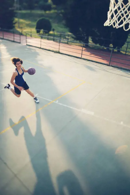 Female athlete running with basketball while practicing on court