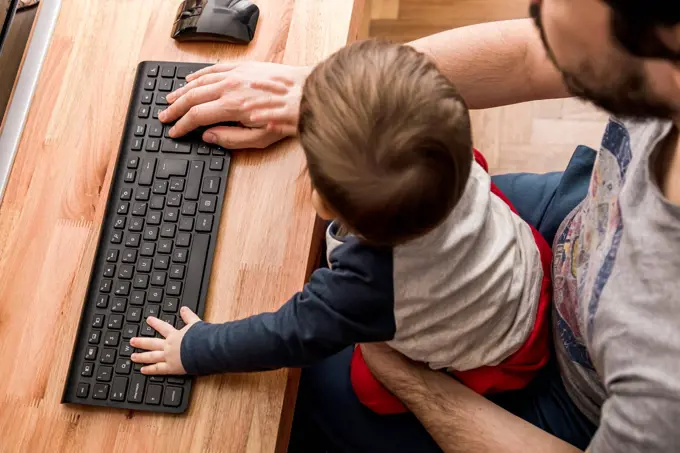 Father working from home with his baby on lap