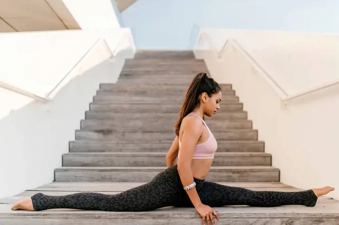 Female athlete with legs apart sitting on wooden steps