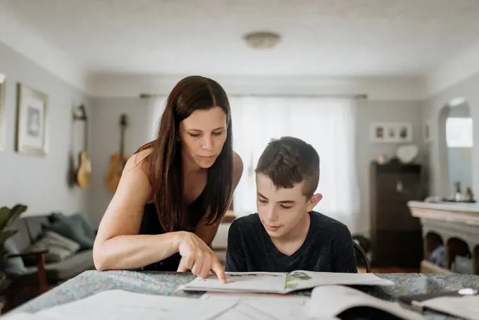 Mother teaching son on table at home during curfew