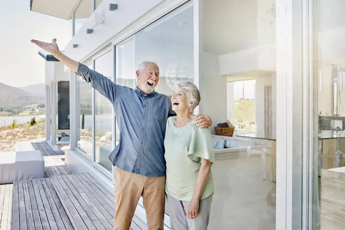 Carefree senior couple standing at luxury beach house