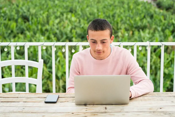 Teenage boy with short hair using laptop at table